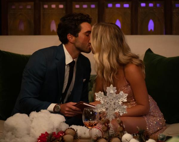 Joey and Daisy sitting on a couch kissing - scene from The Bachelor season premiere as Daisy shares her hearing loss journey.