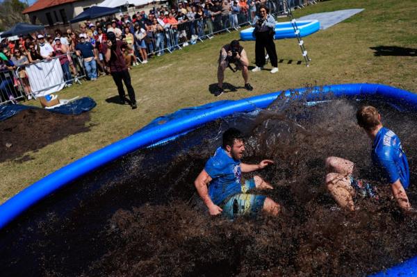 Heyday Schlitt, left, and teammate Schuyler Amacher splash down in a pool, a punishment for the loser, in a relay race called 