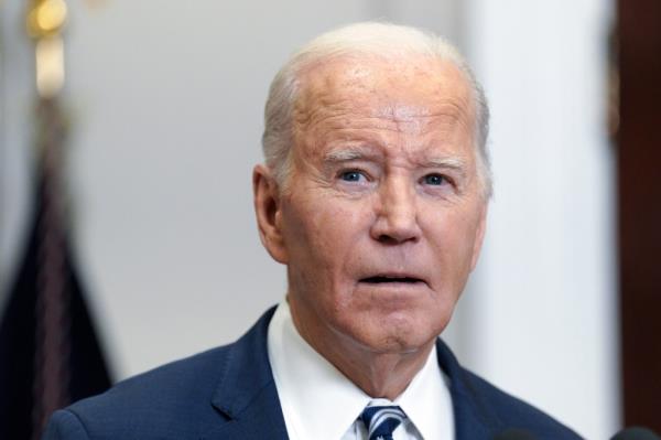 Joe Biden speaking in a room with a US flag behind him.