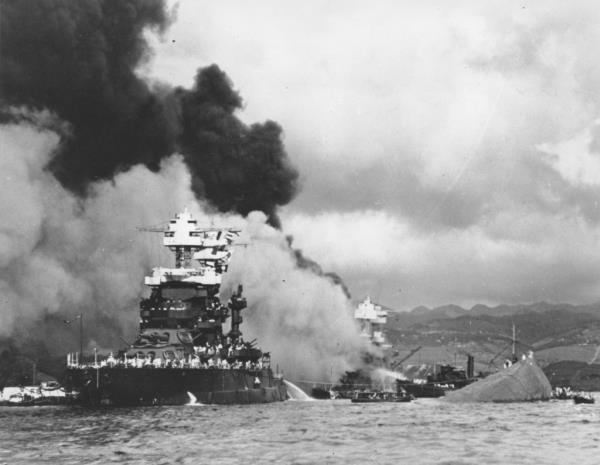 Smoke rises as the hull of the capsized USS Oklahoma sticks out of the water in Pearl Harbor on Dec. 7, 1941. 