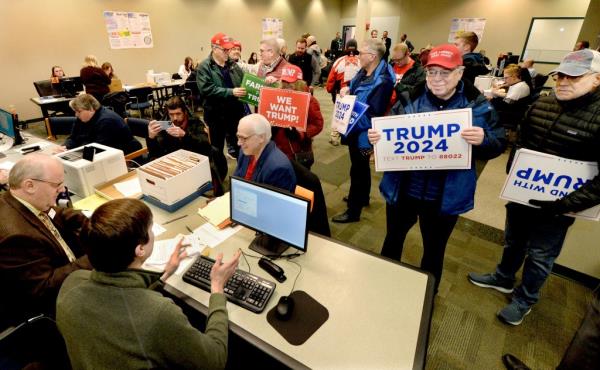 People standing with posters in a room submitting nomination papers to the State Board of Elections for Republican presidential candidate Do<em></em>nald Trump.