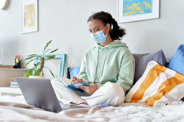 Teenage girl wearing face mask remote studying o<em></em>nline at home. 