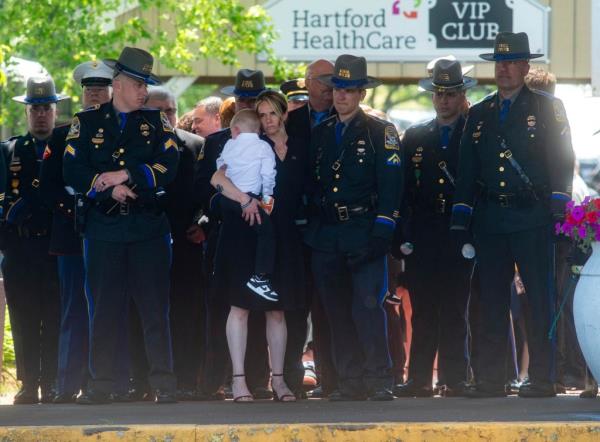 Dominique Pelletier holds one her sons as her husband Co<em></em>nnecticut State trooper Aaron Pelletier's casket is carried out of the Xfinity Theater after his funeral in Hartford, Conn.