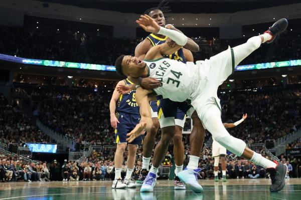 Giannis Antetokounmpo #34 of the Milwaukee Bucks is fouled by Aaron Nesmith #23 of the Indiana Pacers during the second half of a game at Fiserv Forum on December 13, 2023 