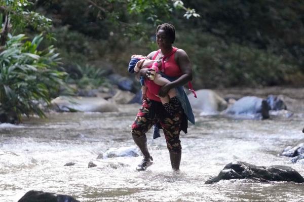 A woman carrying a child as she crosses the Acandi River in Colombia on Sept. 15, 2024.