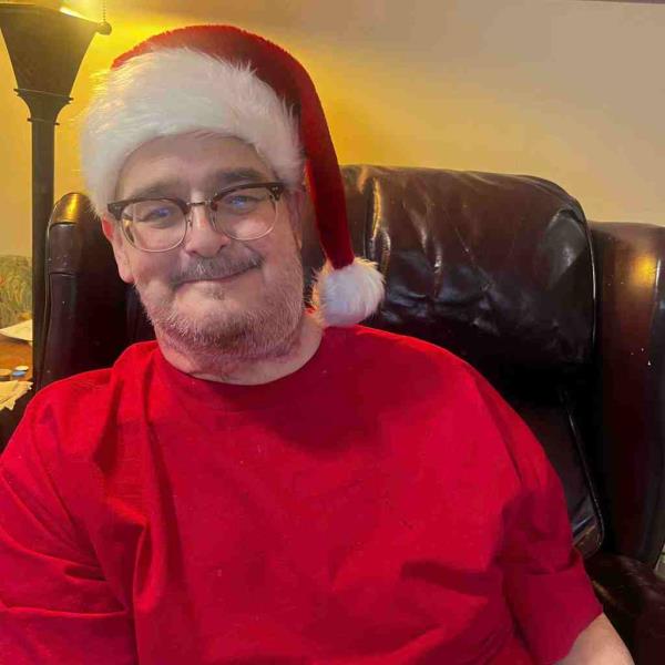 Kevin Campbell in a photo posted Christmas Day on his GoFundMe page. He underwent cancer surgery Dec. 9. He's wearing a red sweatshirt and a red Santa cap and is smiling. He's also wearing glasses.