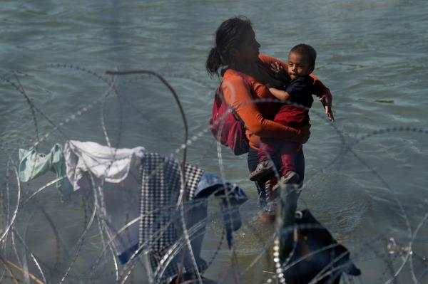 Migrants who crossed into the U.S. from Mexico are met with co<em></em>ncertina wire along the Rio Grande, Thursday, Sept. 21, 2023, in Eagle Pass, Texas. 