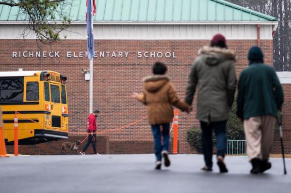 Children and parents walk in front of school
