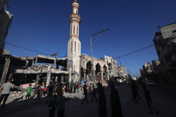 People in Rafah walk next to a building destroyed during an Israeli bombardment in the southern Gaza Strip on April 17, 2024.