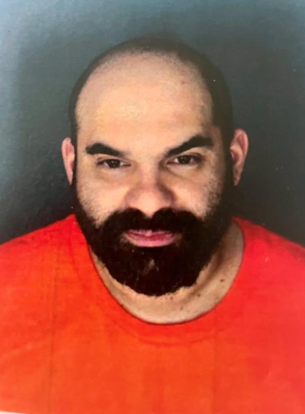 Luiggi Canessa, a bearded 46-year-old man, manager of Shenanigans strip club and adjoining lingerie business, awaiting trial in jail, seen in mugshot wearing orange