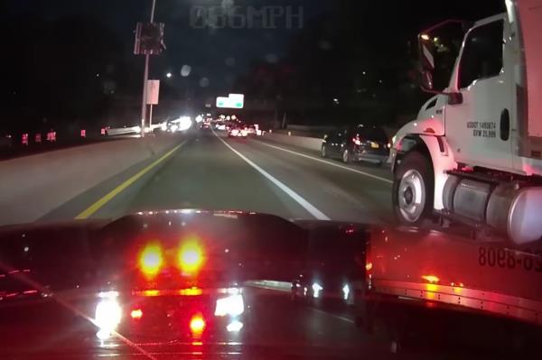 Screenshot of video of motorist driving on Long Island Expressway with rearview recording of police car chasing them with lights flashing.