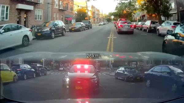 Screenshot of video of motorist driving in Astoria with rearview recording of police car chasing them with lights flashing.