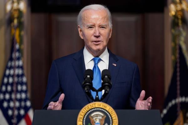 President Joe Biden gestures as he speaks at a lectern with the presidential seal on its front.