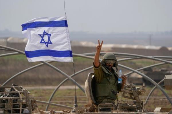An Israeli soldier flashes a V-sign from an armoured perso<em></em>nnel carrier (APC) as they head towards the Gaza Strip border in southern Israel, Saturday, Oct. 14, 2023. (AP Photo/Ariel Schalit)