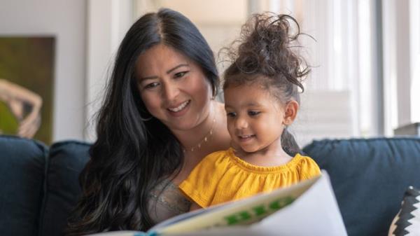A loving mother of Asian descent sits on the couch at home and reads a storybook to her preschool age daughter. The child is sitting on her mother's lap.</p>

<p>　　