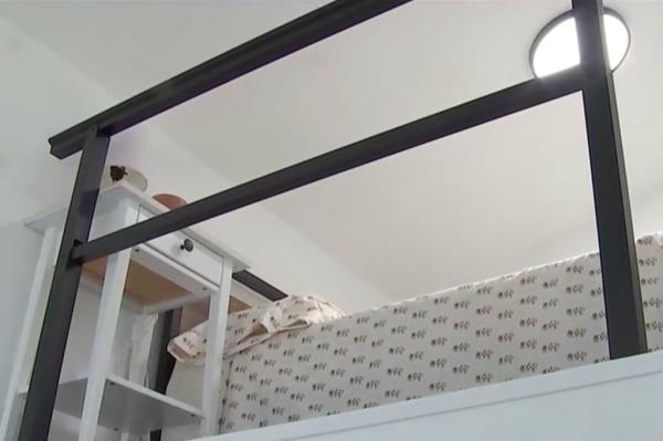 The bed is perched in a lofted space that overlooks the main floor.