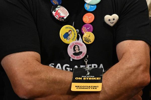 A person wears pins and a SAG-AFTRA negotiating commitee member badge during a press co<em></em>nference 
