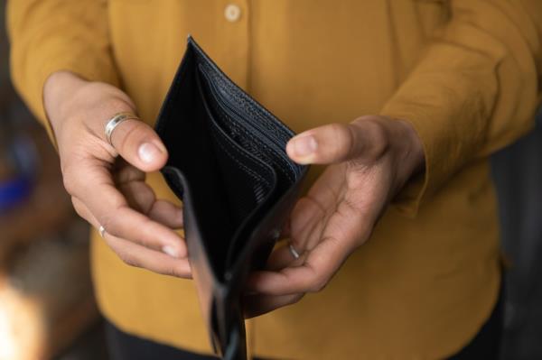 Close up of a stressed young African American woman holding an empty black leather wallet due to financial problems and bankruptcy