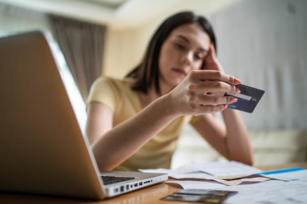 Distressed Asian woman feeling worried a<em></em>bout financial troubles, looking at paperwork and bills in her home