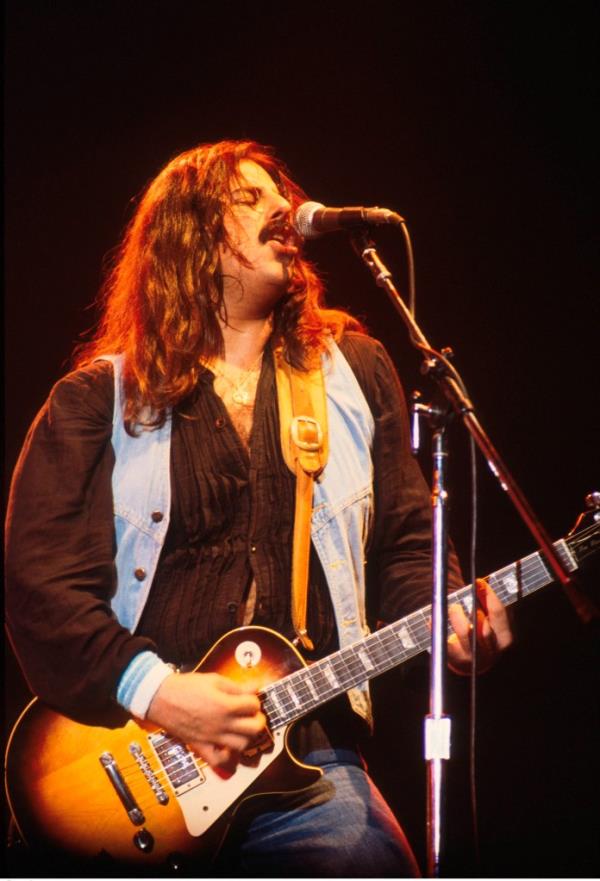 Freddie Salem of The Outlaws performing and singing into a microphone on stage in the UK, 1976