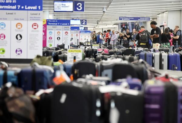 Travelers wait for their bags amid rows of unclaimed luggage at the United Airlines baggage claim area at Los Angeles Internatio<em></em>nal Airport