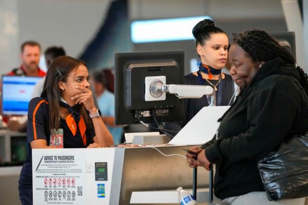 Jet Blue agents help a traveler, right, in the departures area of Terminal B at LaGuardia Airport, Tuesday, June 27, 2023, in New York.