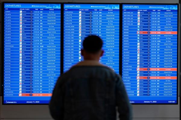 A traveler looks at a flight board with delays and cancellations at Ro<em></em>nald Reagan Washington Natio<em></em>nal Airport in Arlington, Virginia.