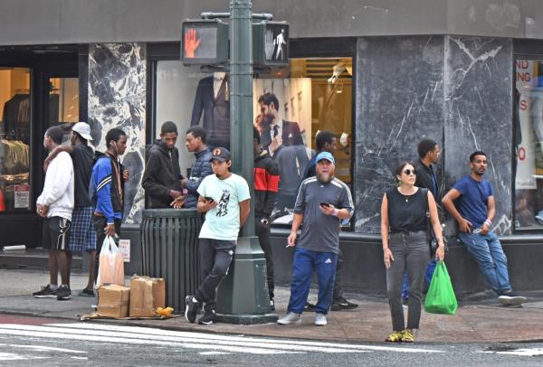 A group of people wait on a corner in Manhattan. 