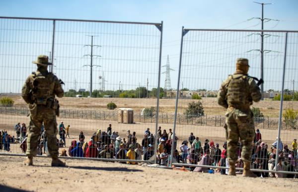  Migrants wait in line adjacent to the border fence under the watch of the Texas Natio<em></em>nal Guard to enter into El Paso, Texas, May 10, 2023. 