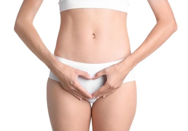 Young woman in white underwear holding hands in a heart shape in front of her vagina