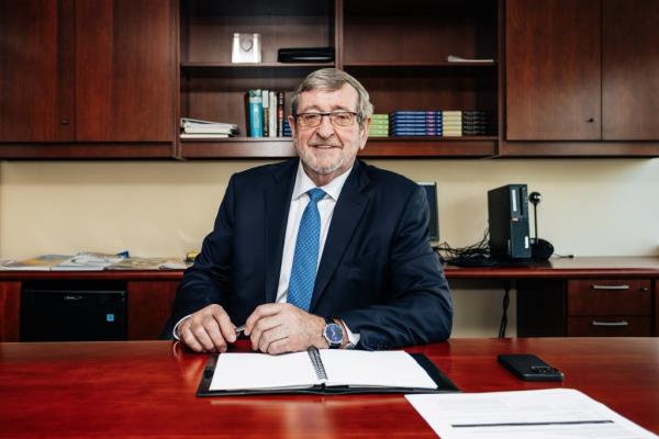 Michael Dowling, wearing a suit and sitting at a desk at Northwell's Corporate Headquarters in Manhattan, photographed on October 9, 2024.