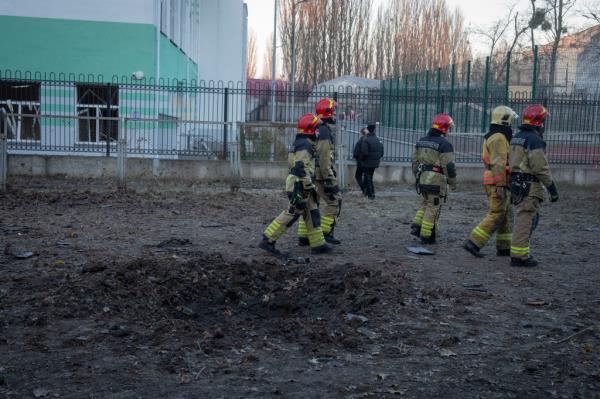 Firefighters pass by a crater left by drone fragments in an apartment building yard following a Russian drone attack in Kyiv, Ukraine, Saturday, Nov. 25, 2023. Russia launched its most intense drone attack on Ukraine since the beginning of its full-scale invasion on Saturday morning, military officials said. (AP Photo/Efrem Lukatsky)