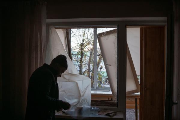 A man uses plastic to cover a broken window in his apartment following a Russian drone attack in Kyiv, Ukraine, Saturday, Nov. 25, 2023. Russia launched its most intense drone attack on Ukraine since the beginning of its full-scale invasion on Saturday morning, military officials said. (AP Photo/Felipe Dana)