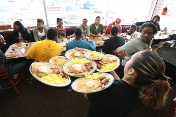 Denny's waitress, resembling Jaime Staples, delivering free Grand Slam breakfasts to customers during a special promotion