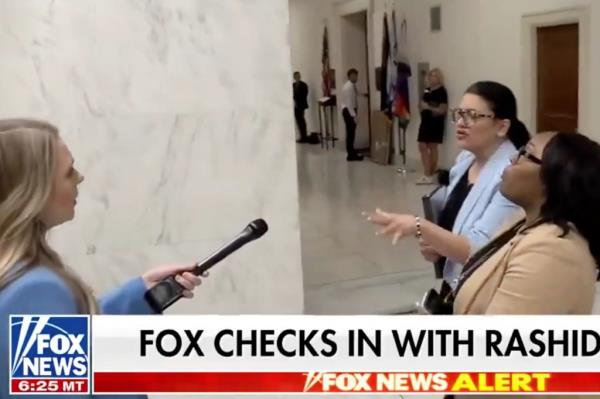 Rep. Rashida Tlaib holding a microphone and talking to a Fox Business reporter at a rally in her district