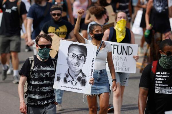 Demo<em></em>nstrators holding signs during a rally and march over the death of Elijah McClain