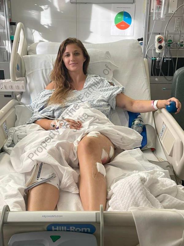 Julia Fatum laying in a hospital bed, with bandages covering the stab wounds in her left leg
