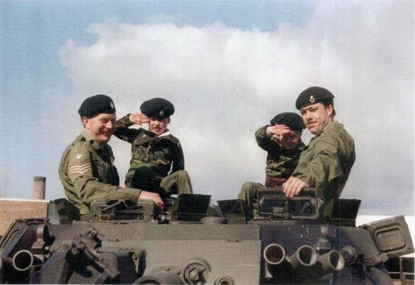 Prince Harry (2nd from R) and Prince William (2nd from L), sit on a tank dressed in combat fatigues whilst visiting Combermere Barracks.