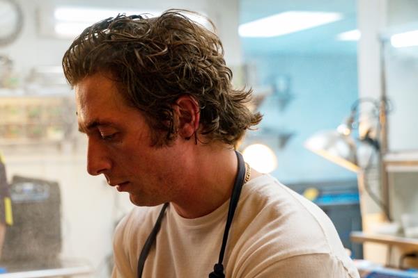 Jeremy Allen White in a kitchen in an apron. 