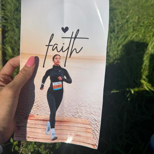 A hand holding a photo of Valdes running with the word 