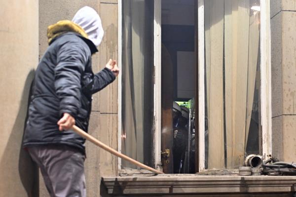 A protester uses a wooden object against police officers guarding the entrance to the Belgrade's city council building during a demo<em></em>nstration in Belgrade, on December 24, 2023,