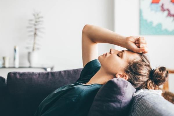 A woman looking ill on a sofa.